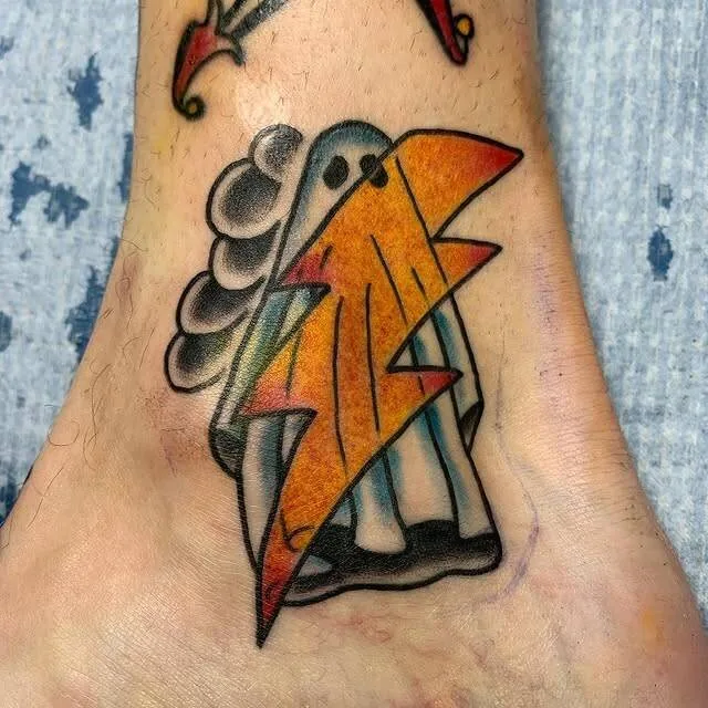 Small American Traditional tattoo of a sheet ghost holding a bright orange lightning bolt on the top of the foot, by Forrest Goodrich at Ohana Tattoo, Waikiki, Hawaii.